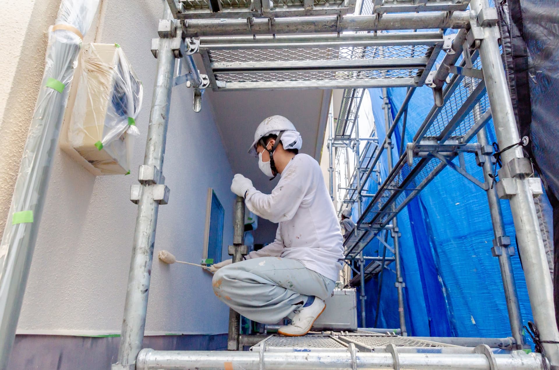 外壁塗装をする作業員の様子が写っている